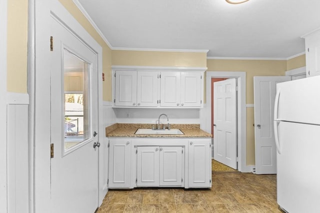 kitchen featuring white cabinetry, crown molding, sink, and white fridge