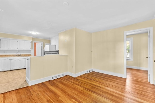 kitchen featuring white cabinetry, sink, refrigerator, and light hardwood / wood-style flooring