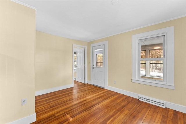 empty room with hardwood / wood-style flooring and crown molding