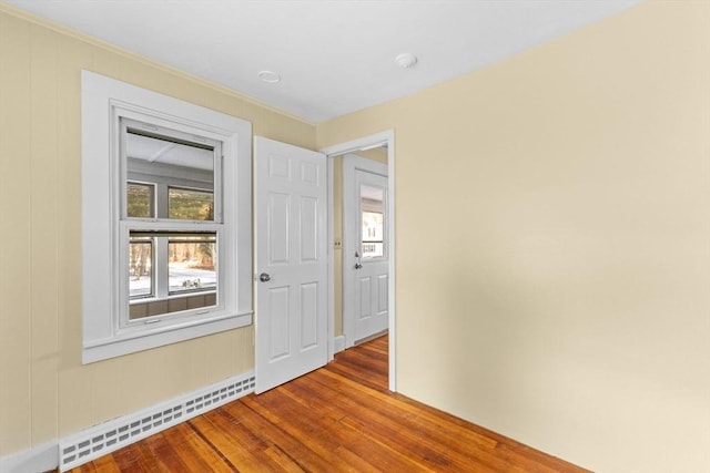 unfurnished room featuring hardwood / wood-style floors, plenty of natural light, and baseboard heating