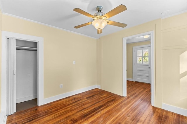 unfurnished bedroom with ceiling fan, wood-type flooring, a closet, and ornamental molding