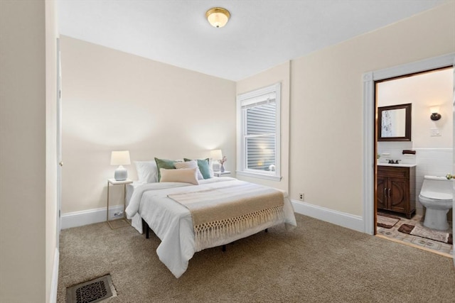 carpeted bedroom with ensuite bathroom, visible vents, and baseboards