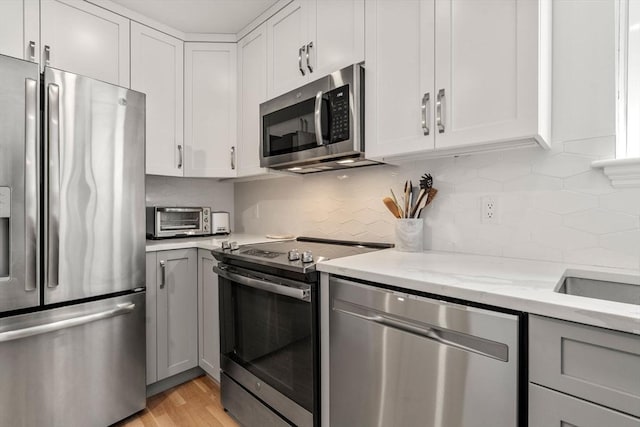 120 Norway St Unit 12, Boston, MA 02115 - kitchen featuring appliances with stainless steel finishes, backsplash, light stone countertops, and white cabinets