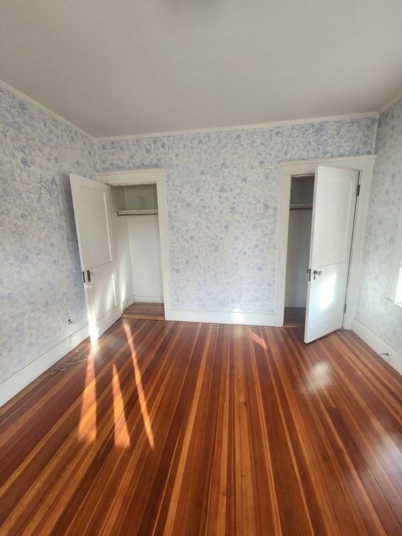 unfurnished bedroom with ornamental molding, dark hardwood / wood-style floors, and a closet