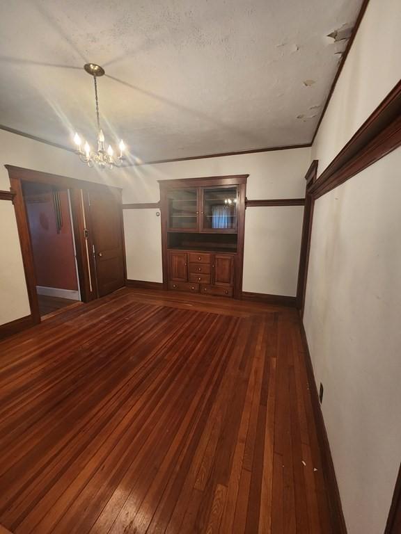 unfurnished living room featuring an inviting chandelier and dark hardwood / wood-style floors