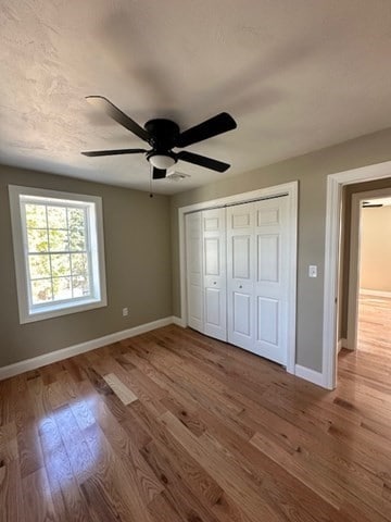 unfurnished bedroom featuring hardwood / wood-style flooring, ceiling fan, and a closet