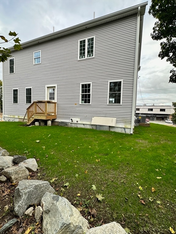 rear view of property with a lawn and central air condition unit