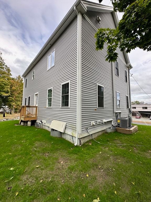 view of side of home with a yard and central AC