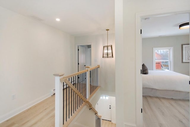 hallway featuring baseboards, wood finished floors, baseboard heating, an upstairs landing, and recessed lighting