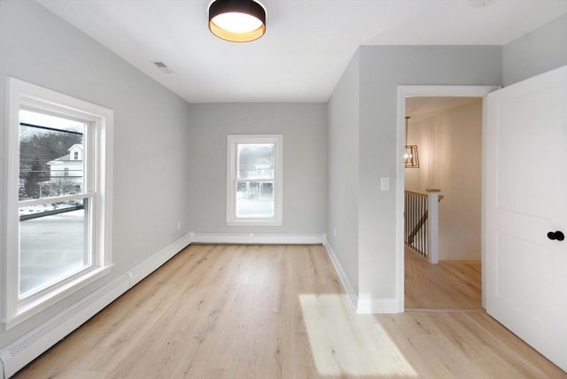 spare room with a healthy amount of sunlight, light wood-style flooring, baseboards, and baseboard heating