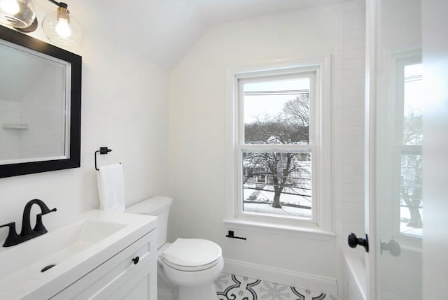 bathroom featuring toilet, lofted ceiling, a wealth of natural light, and baseboards