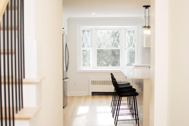 interior space with radiator, baseboards, and light wood finished floors