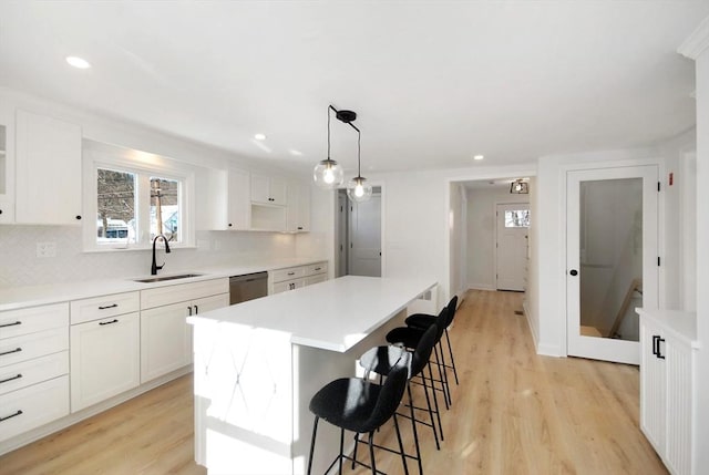 kitchen featuring light wood finished floors, a kitchen island, a kitchen breakfast bar, and a sink