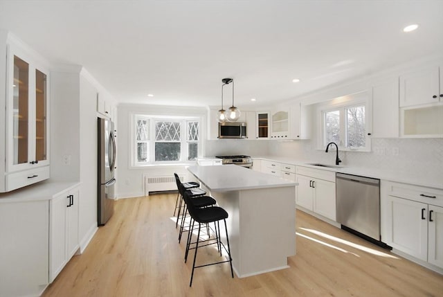 kitchen featuring a center island, a breakfast bar, radiator heating unit, appliances with stainless steel finishes, and a sink