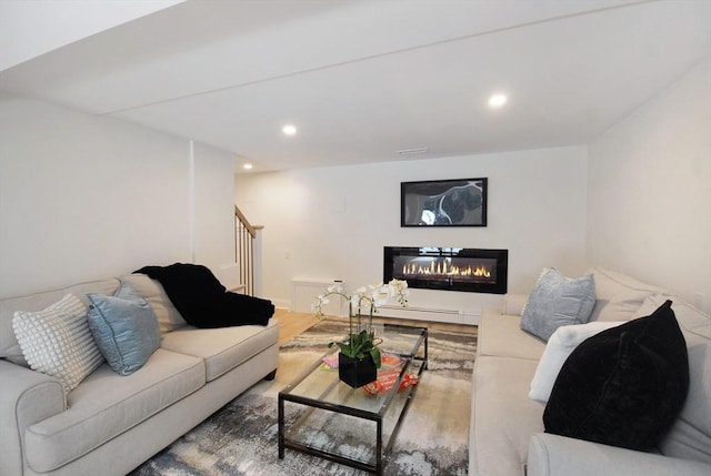 living area featuring a glass covered fireplace, wood finished floors, stairway, and recessed lighting