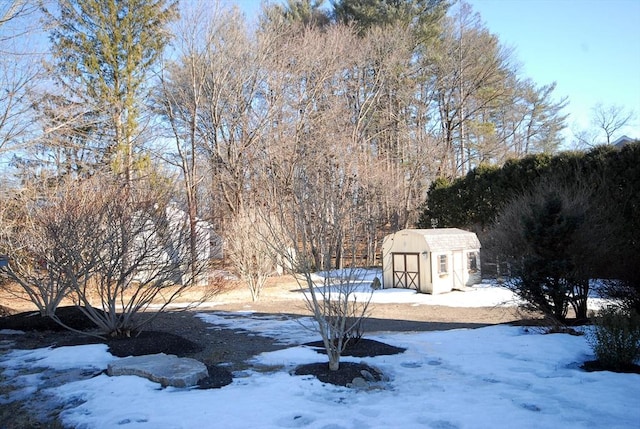 yard layered in snow featuring a storage unit and an outbuilding