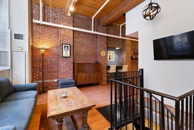 living room featuring brick wall, a towering ceiling, wood ceiling, and beamed ceiling