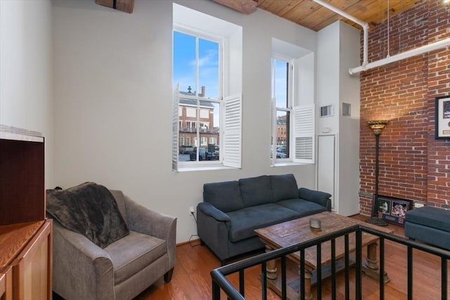 living room with brick wall, wooden ceiling, a fireplace, and hardwood / wood-style flooring