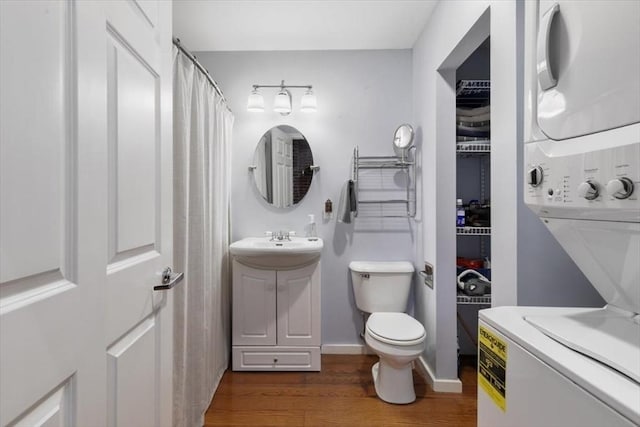 bathroom featuring sink, curtained shower, stacked washer / dryer, toilet, and wood-type flooring