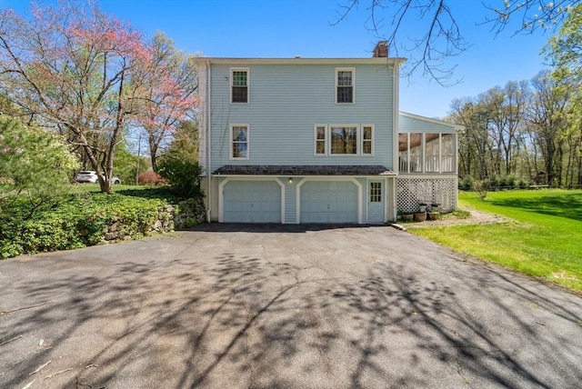 16 Parmenter Rd, Framingham, MA 01701 - view of side of property featuring driveway, a chimney, an attached garage, a sunroom, and a yard
