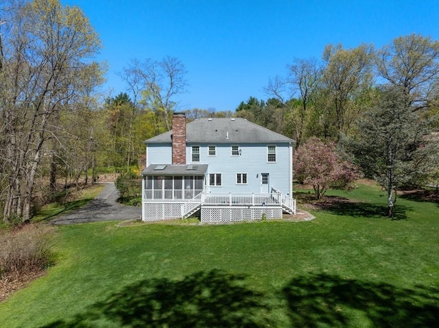 16 Parmenter Rd, Framingham, MA 01701 - back of property featuring a sunroom, a chimney, a lawn, a deck, and roof with shingles
