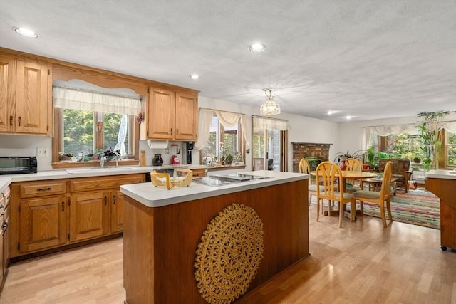 16 Parmenter Rd, Framingham, MA 01701 - kitchen featuring light countertops, stainless steel cooktop, a center island, light wood-type flooring, and healthy amount of natural light