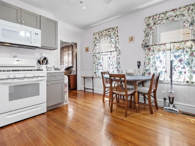 210-212 Brown St, Waltham, MA 02453 - kitchen featuring white appliances, gray cabinetry, light wood finished floors, a ceiling fan, and a wainscoted wall