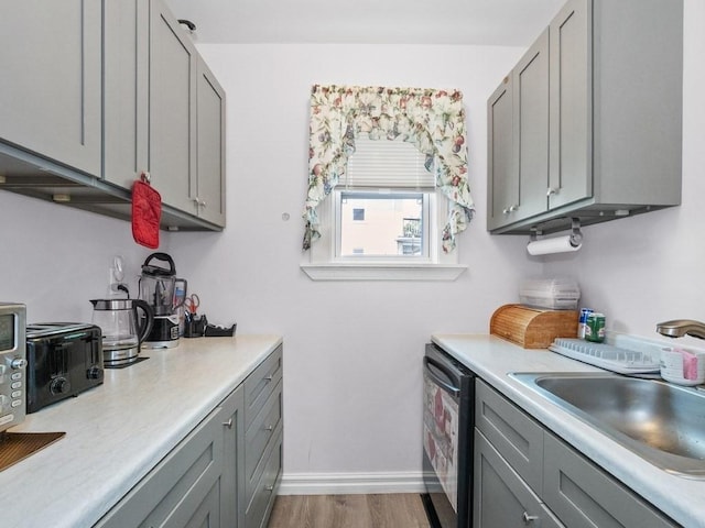 210-212 Brown St, Waltham, MA 02453 - kitchen with gray cabinetry, light countertops, dishwashing machine, and light wood-style flooring