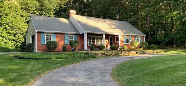 view of front of home with a front yard, brick siding, and a chimney