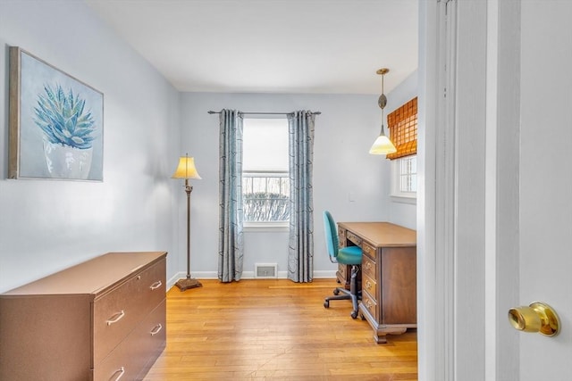 office space featuring light wood finished floors, visible vents, baseboards, and a wealth of natural light