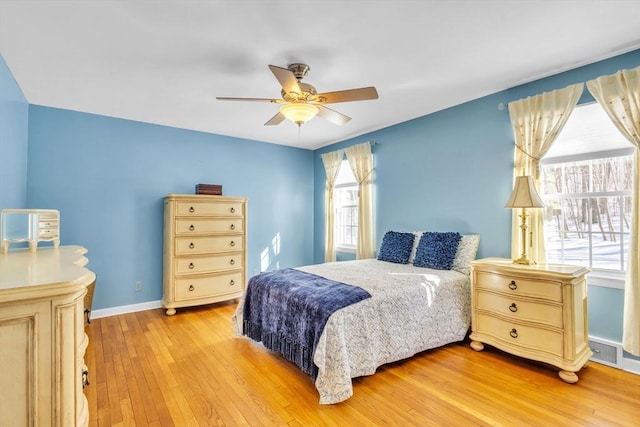 bedroom featuring visible vents, light wood-style flooring, a ceiling fan, and baseboards