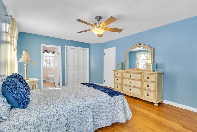 bedroom featuring wood finished floors, baseboards, ceiling fan, a closet, and ensuite bathroom