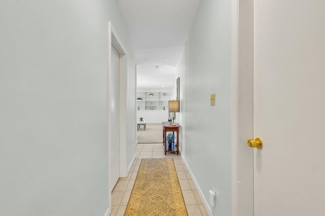 hallway featuring light tile patterned floors and baseboards