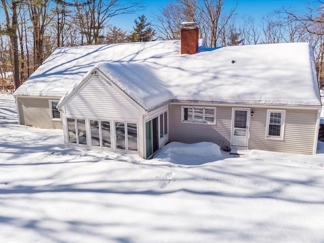 snow covered property featuring a chimney and a sunroom