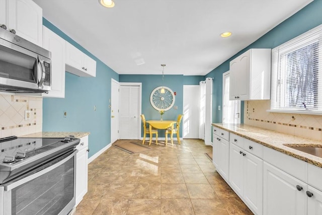 kitchen featuring baseboards, light stone countertops, appliances with stainless steel finishes, and white cabinetry