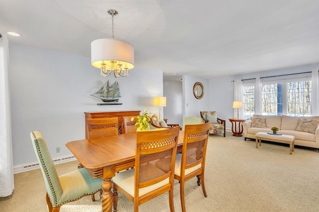 dining room featuring a chandelier, light colored carpet, and baseboards