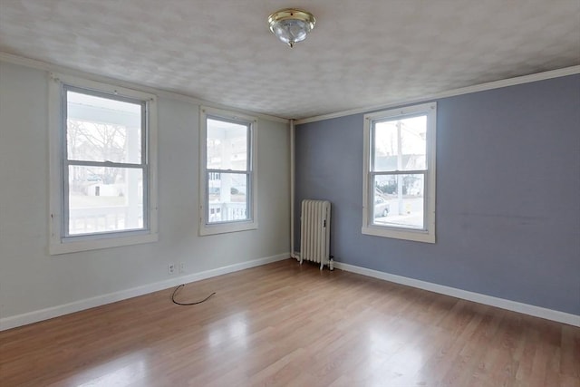 unfurnished room featuring light wood-type flooring, radiator, and crown molding