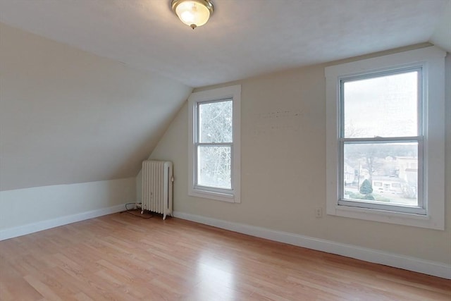 bonus room featuring light wood-type flooring, plenty of natural light, radiator, and lofted ceiling