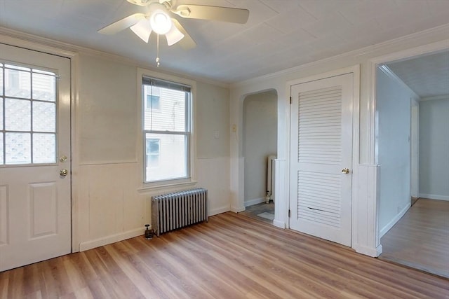 interior space featuring ceiling fan, radiator heating unit, crown molding, and light hardwood / wood-style flooring