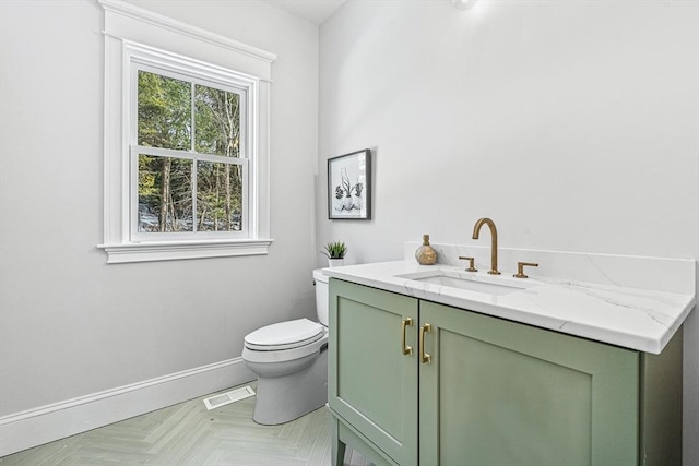 bathroom featuring toilet, vanity, and parquet flooring