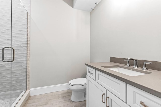 bathroom featuring toilet, vanity, a shower with shower door, and wood-type flooring