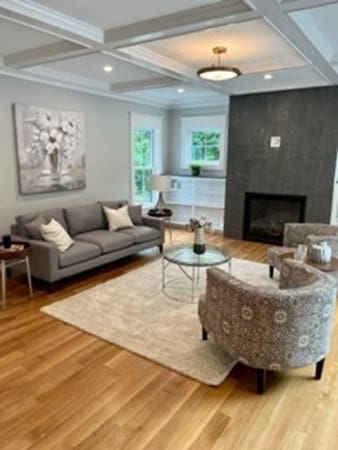 living room featuring coffered ceiling, hardwood / wood-style flooring, a high end fireplace, and beam ceiling