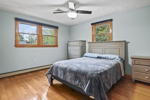 bedroom featuring multiple windows, hardwood / wood-style flooring, and baseboard heating