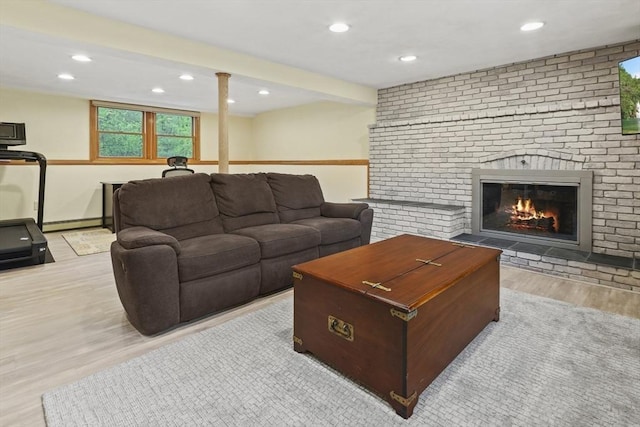 living area featuring wood finished floors, a baseboard heating unit, recessed lighting, and a brick fireplace