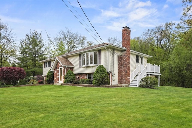 view of front facade featuring a chimney, a front yard, stairway, a wooden deck, and brick siding