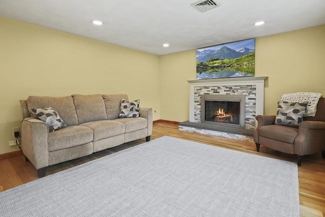 living room featuring wood finished floors, a fireplace, baseboards, and recessed lighting
