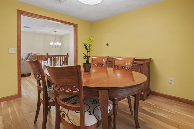 dining space featuring light wood-style flooring, baseboards, and a chandelier