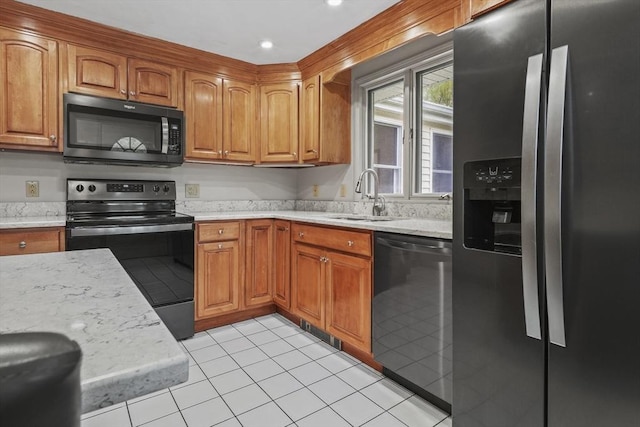 kitchen featuring appliances with stainless steel finishes, a sink, brown cabinetry, light stone counters, and recessed lighting