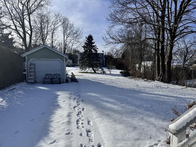 yard layered in snow with a garage and an outbuilding