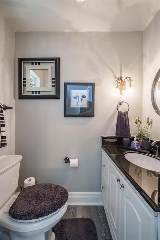 bathroom featuring baseboards, vanity, toilet, and wood finished floors